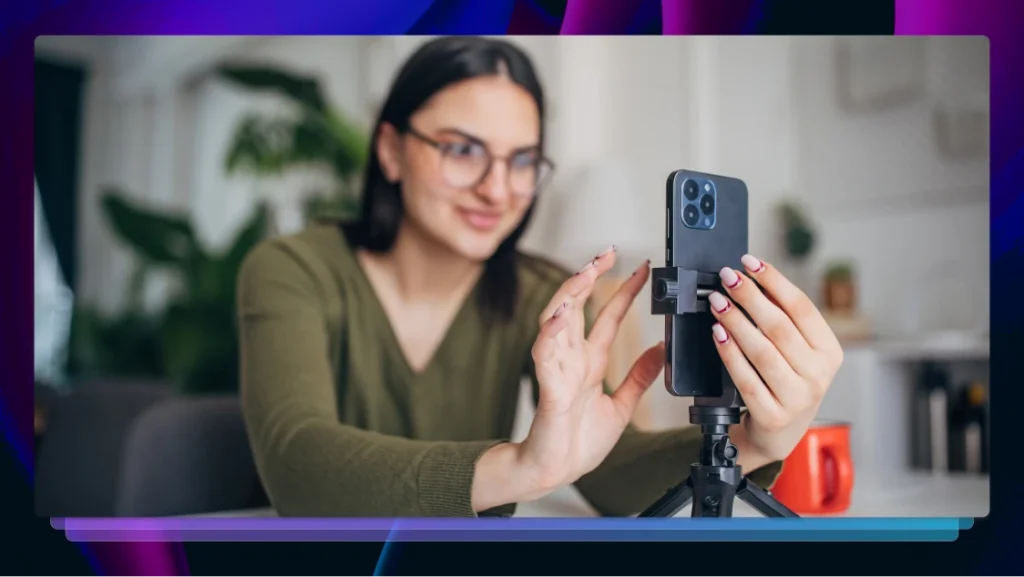 Woman holding an iPhone mounted on a small tripod and tapping the screen to adjust video.