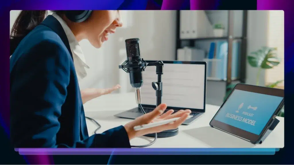 A female podcaster speaking into a microphone in front of a tablet and a laptop