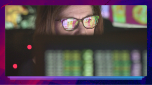 Woman looking at a computer with on-screen images reflecting off her glasses