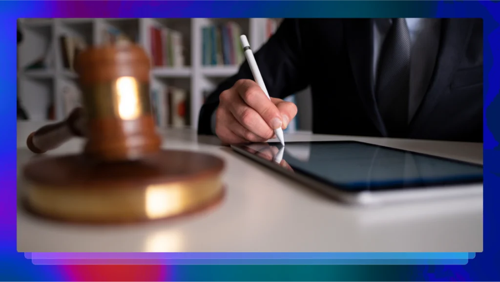 Professionally dressed man at a desk writing with a pen on a tablet next to a gavel.